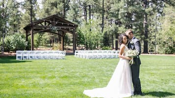Una ceremonia de boda al aire libre con un quiosco de madera y filas de sillas blancas.