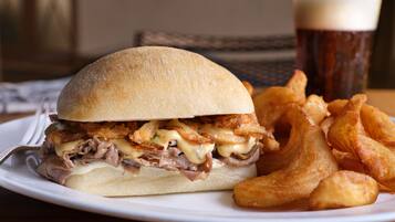 A plate with a sandwich and fries, and a glass of beer.