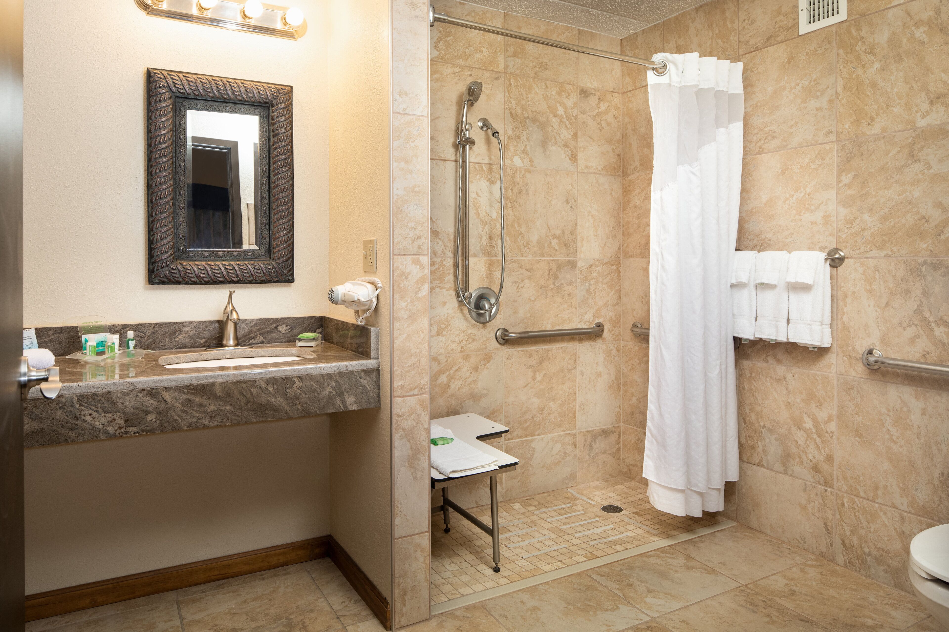 A bathroom with a sink, mirror, shower, and toilet.