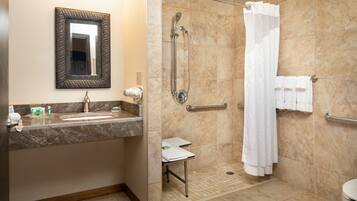 A bathroom with a sink, mirror, shower, and toilet.
