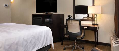Une chambre d’hôtel équipée d’un lit, d’un bureau avec une chaise, d’une télévision, d’une lampe et d’un radiateur.