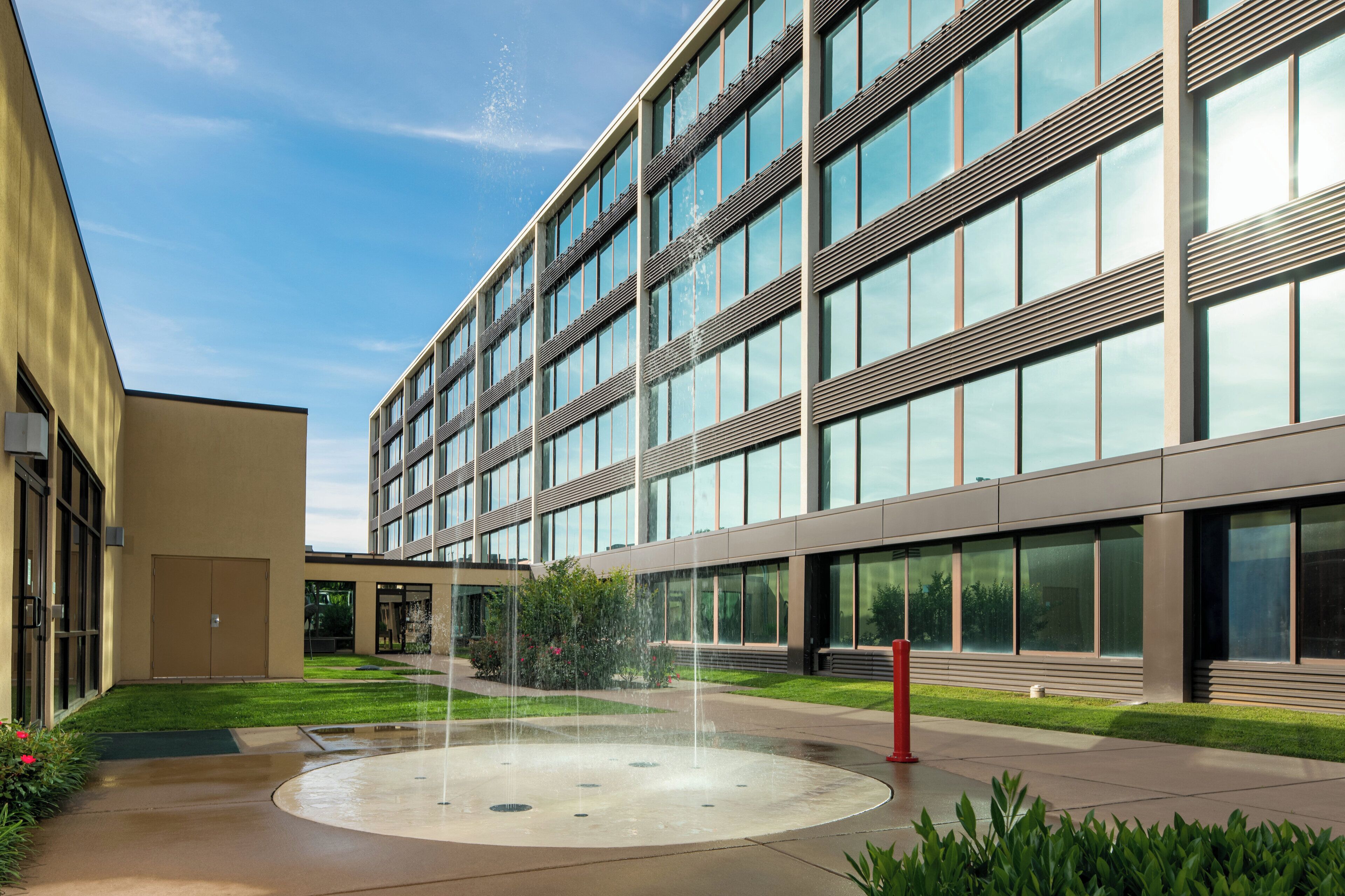 A modern building with a courtyard featuring a circular water fountain.