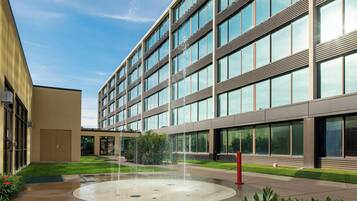 A modern building with a courtyard featuring a circular water fountain.