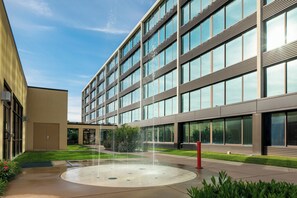 A modern building with a courtyard featuring a circular water fountain. - Holiday Inn Hotel & Suites Charleston West by IHG (South Charleston)