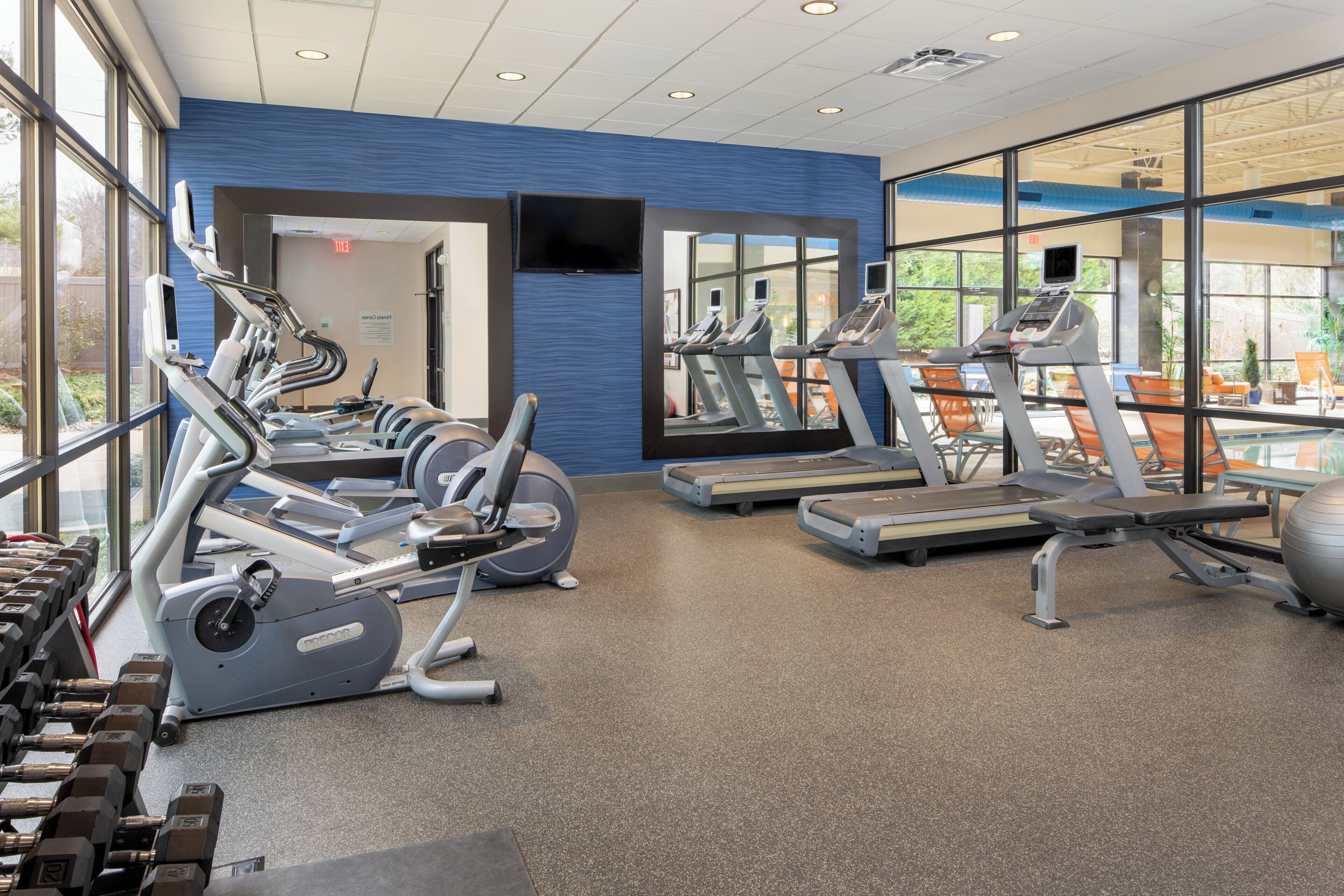 A gym with cardio equipment, weight machines, and a mirror wall.