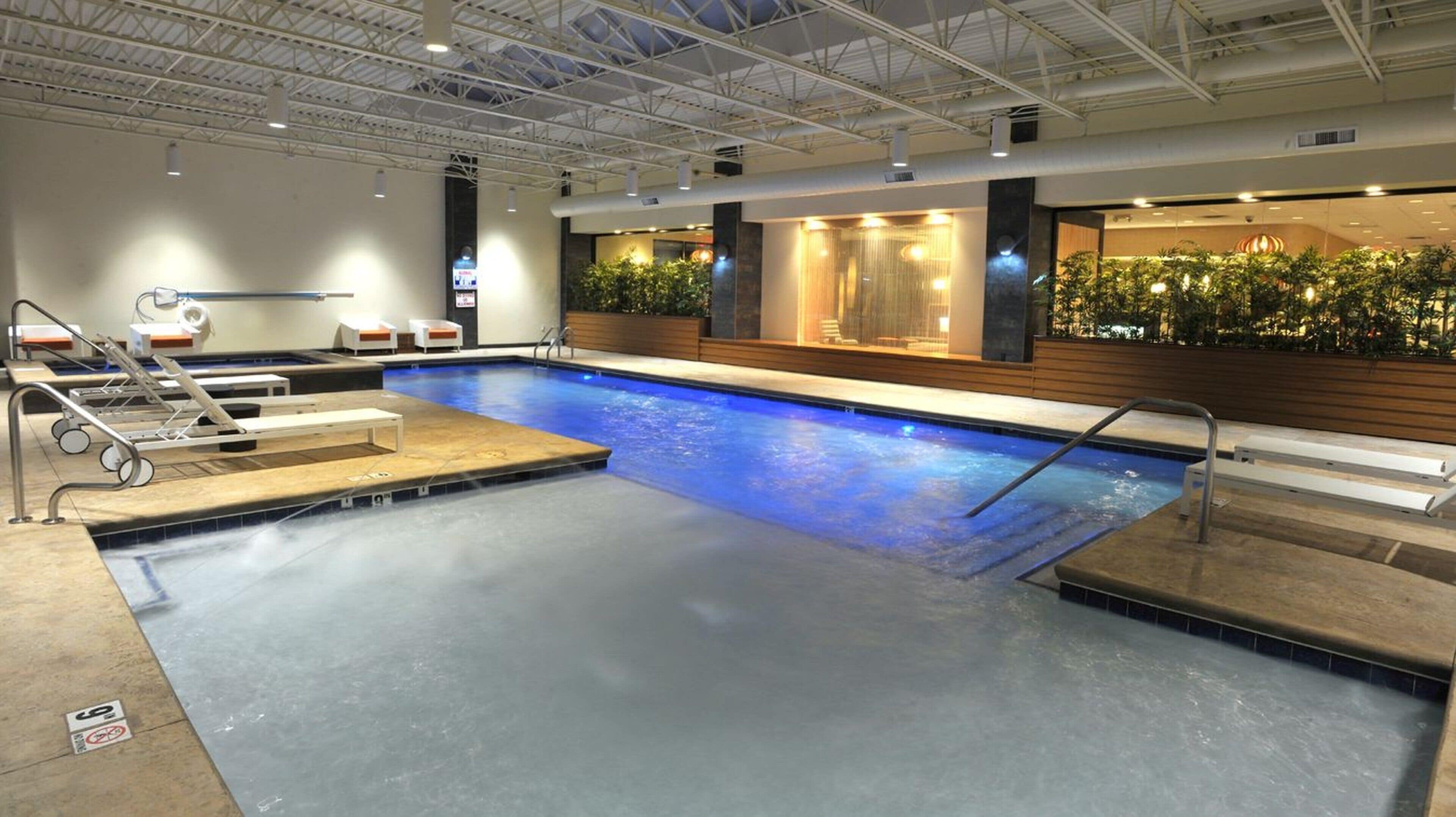 A swimming pool with a water slide, lounge chairs, and a reception area with plants.