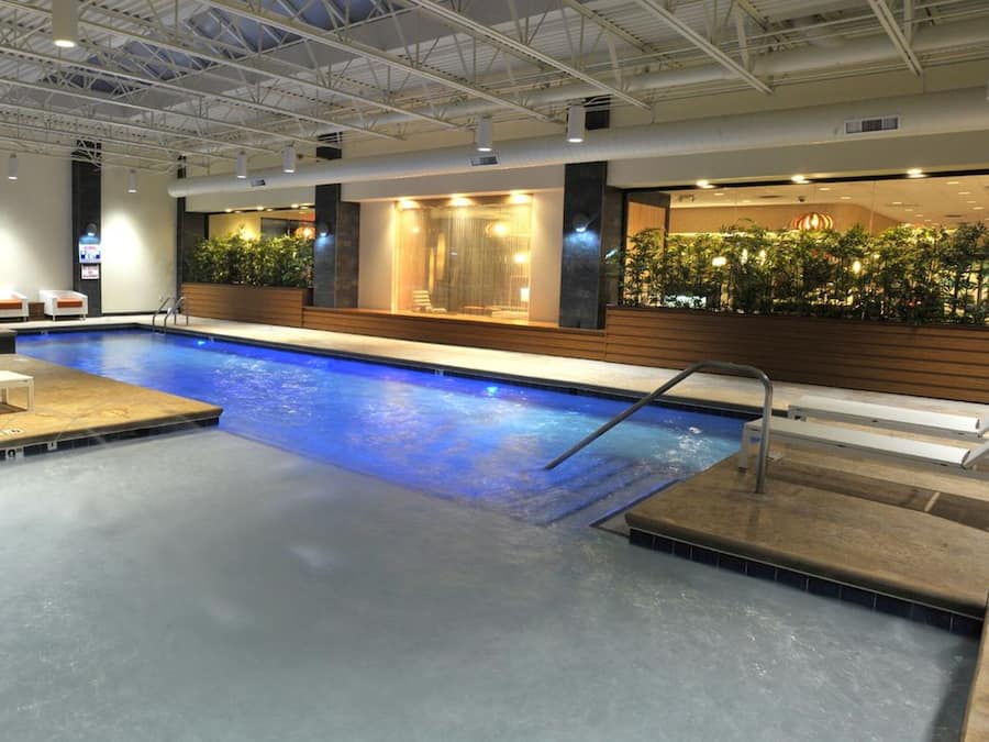 Une piscine avec un toboggan, des chaises longues et un espace d’accueil agrémenté de plantes.