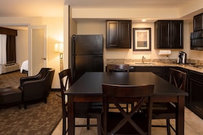 A hotel room with a dining area, a refrigerator, a coffee maker, and a lamp. - Holiday Inn Hotel & Suites Charleston West by IHG (South Charleston)