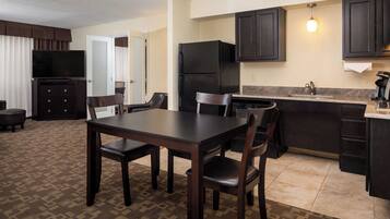 A compact hotel room with a dining area, kitchenette, and a television.