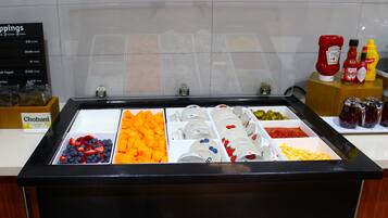 Un bufé de desayuno con diversas frutas, quesos y acompañamientos.