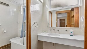 A modern bathroom with a glass-enclosed shower, a white sink, and a mirror with a wooden frame. - Martin Cash Motel (Moonah)