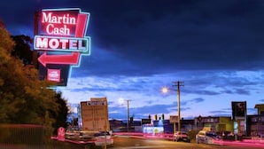 A neon-lit motel sign, Martin Cash Motel, with a clear view of the surrounding roadside and buildings. - Martin Cash Motel (Moonah)