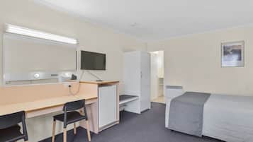 A hotel room with a desk, two chairs, a bed, a TV, a wardrobe, and a painting on the wall.