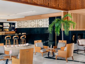 A modern lobby with a bar area, seating arrangements, and a decorative wall with geometric patterns. - Mövenpick Hotel Karachi (Karachi)