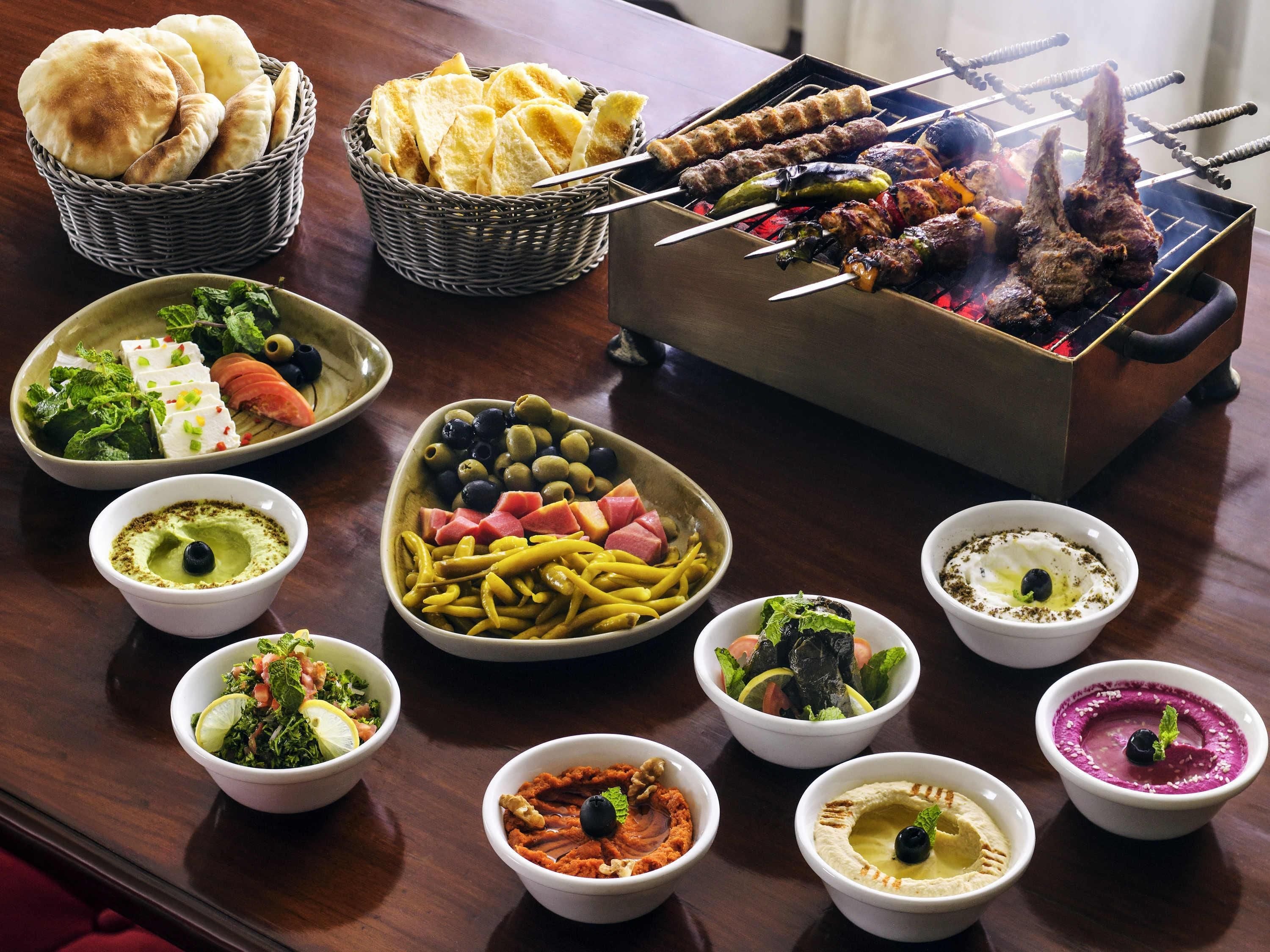 A variety of food items including grilled meats, flatbreads, and dips on a table.