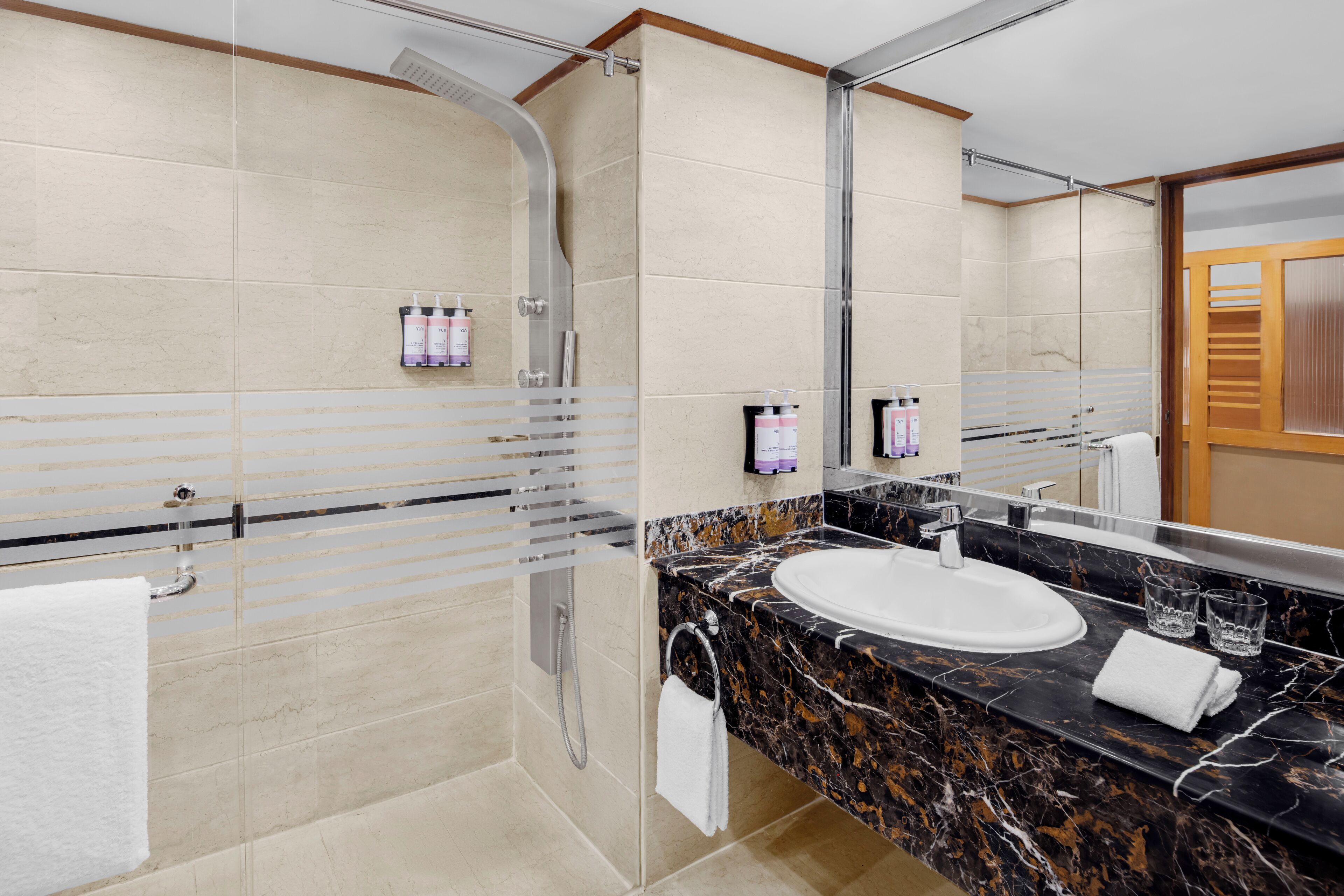 A modern bathroom with a glass shower enclosure, a marble sink, and a large mirror.