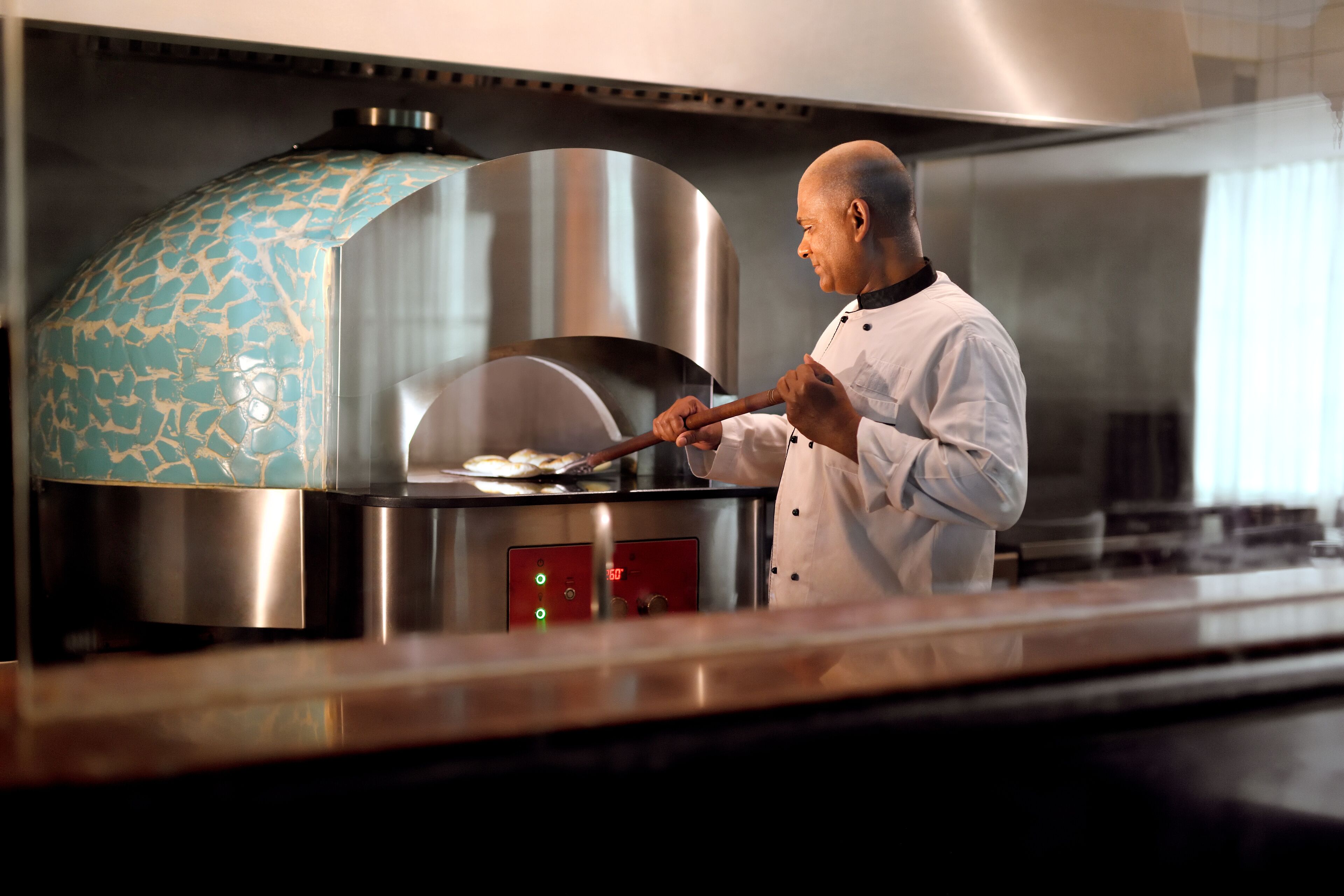 A chef cooking in a professional kitchen with a large, modern oven and stainless steel equipment.