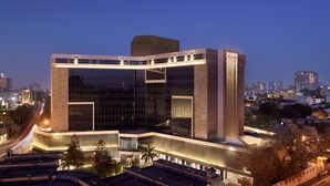 A modern hotel with a prominent corner design, large glass windows, and a well-lit facade.