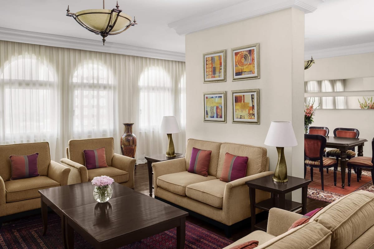A living room with two sofas, a coffee table, a dining table with chairs, and artwork on the wall.