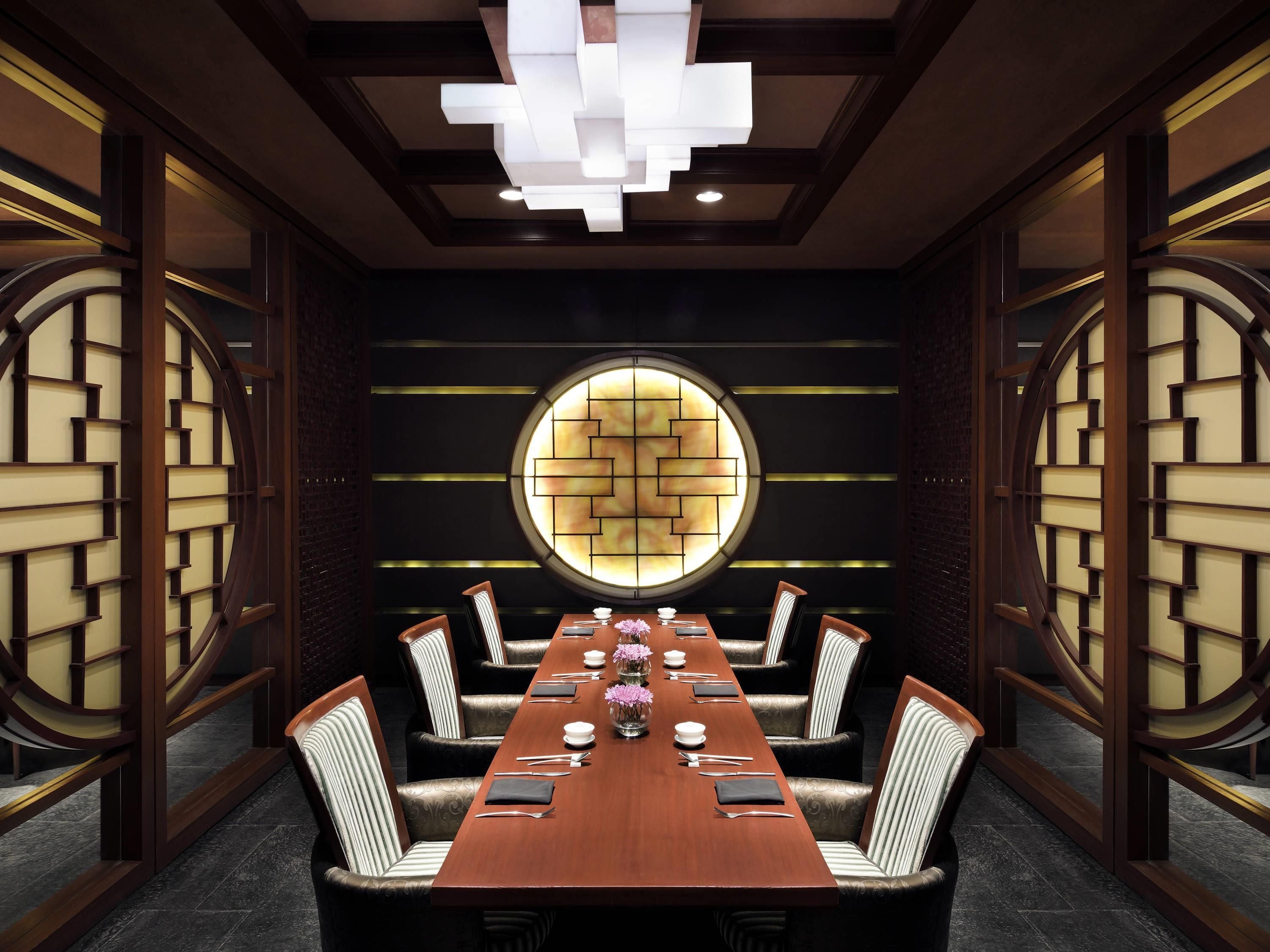 A conference room with a long table, chairs, and a decorative wall with a circular window.