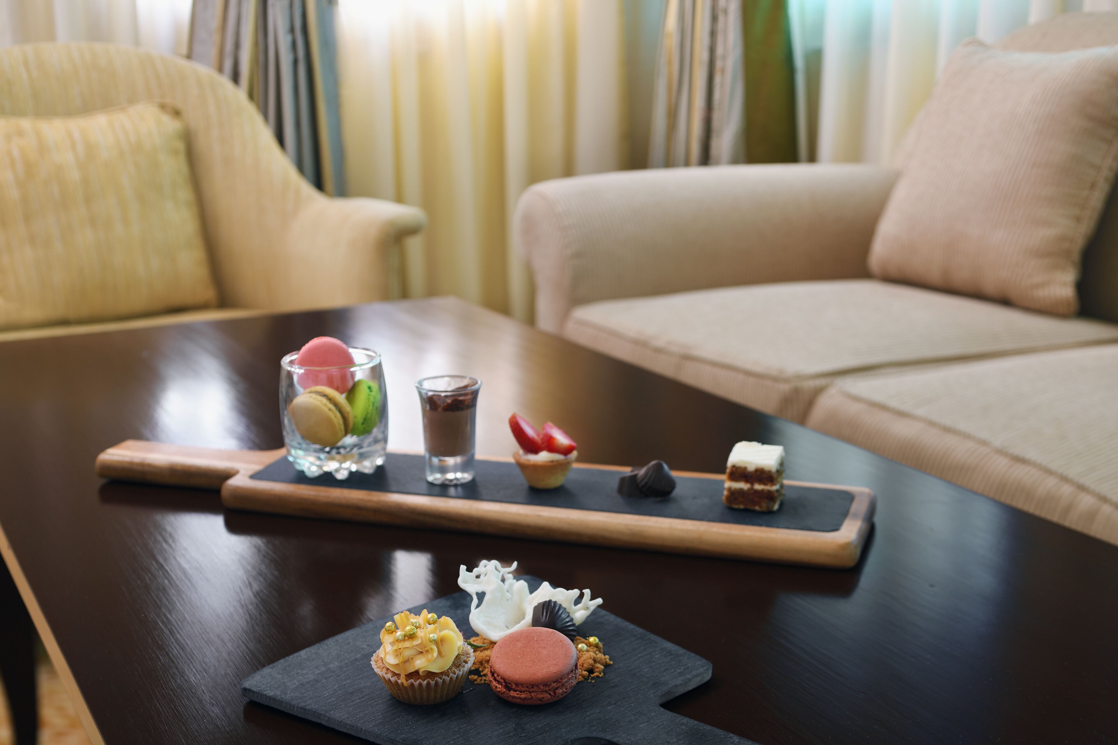 A dining table with a variety of desserts and a glass of a dark beverage.