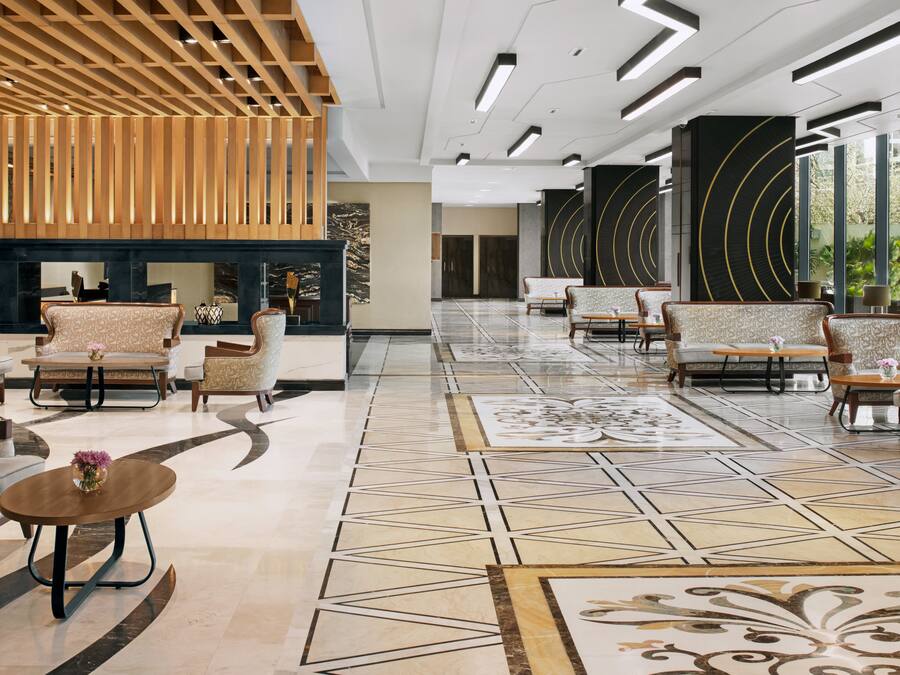 Un vestíbulo amplio con mobiliario moderno, piso estampado y estructura de techo de madera.