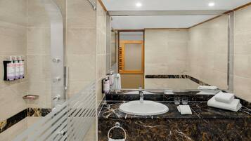 Un baño moderno con lavamanos de mármol, cabina de ducha de vidrio y un perchero para toallas.