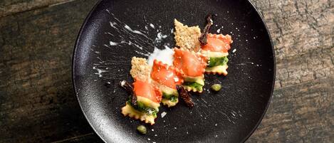 A black plate with food on a wooden surface.