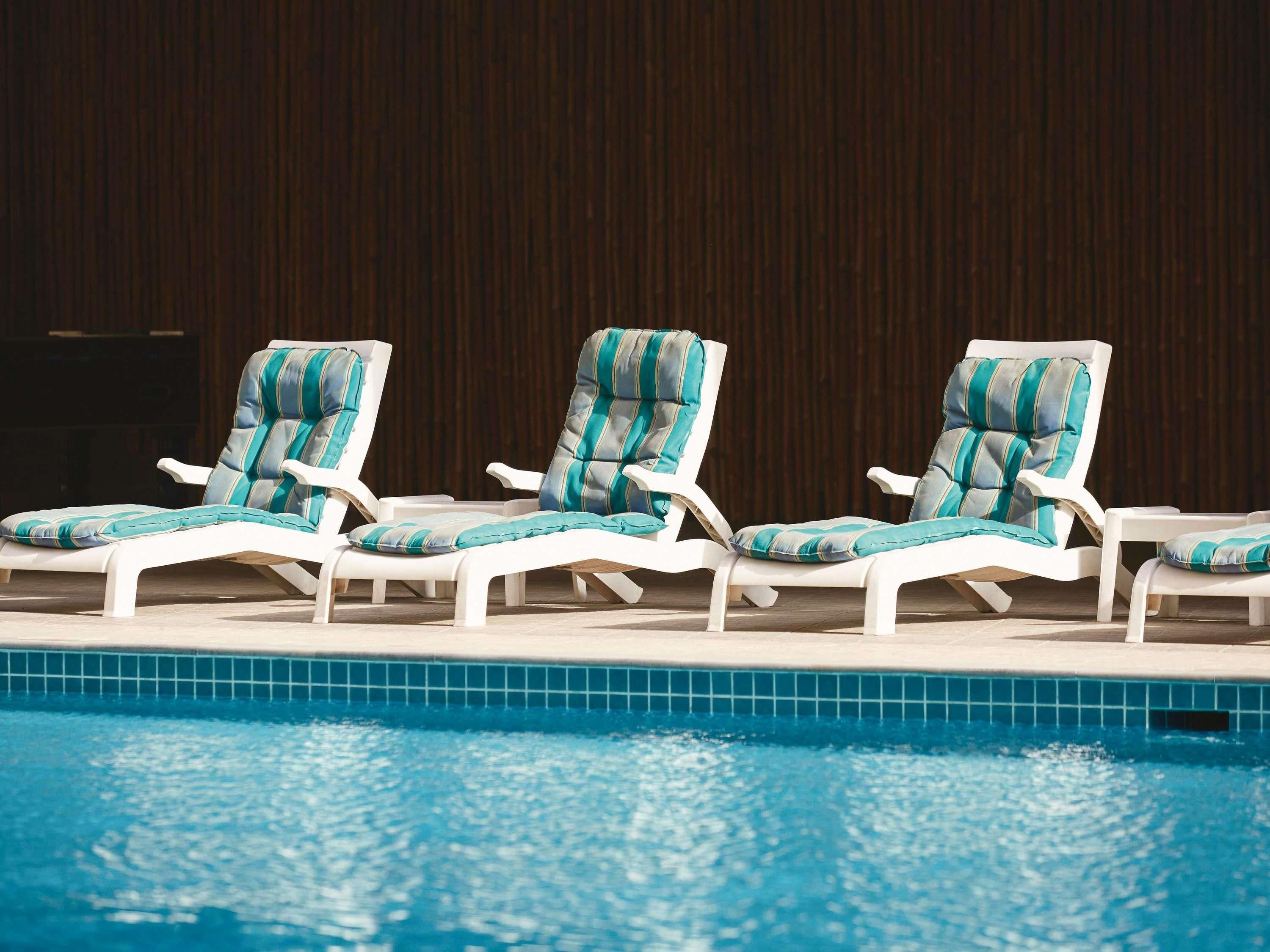 Un área junto a la piscina con sillas de descanso y una piscina con azulejos.