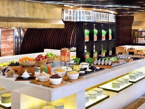 A buffet setup with various food items and drinks, including fruits, cheeses, and a large beverage dispenser. - Mövenpick Hotel Karachi (Karachi)