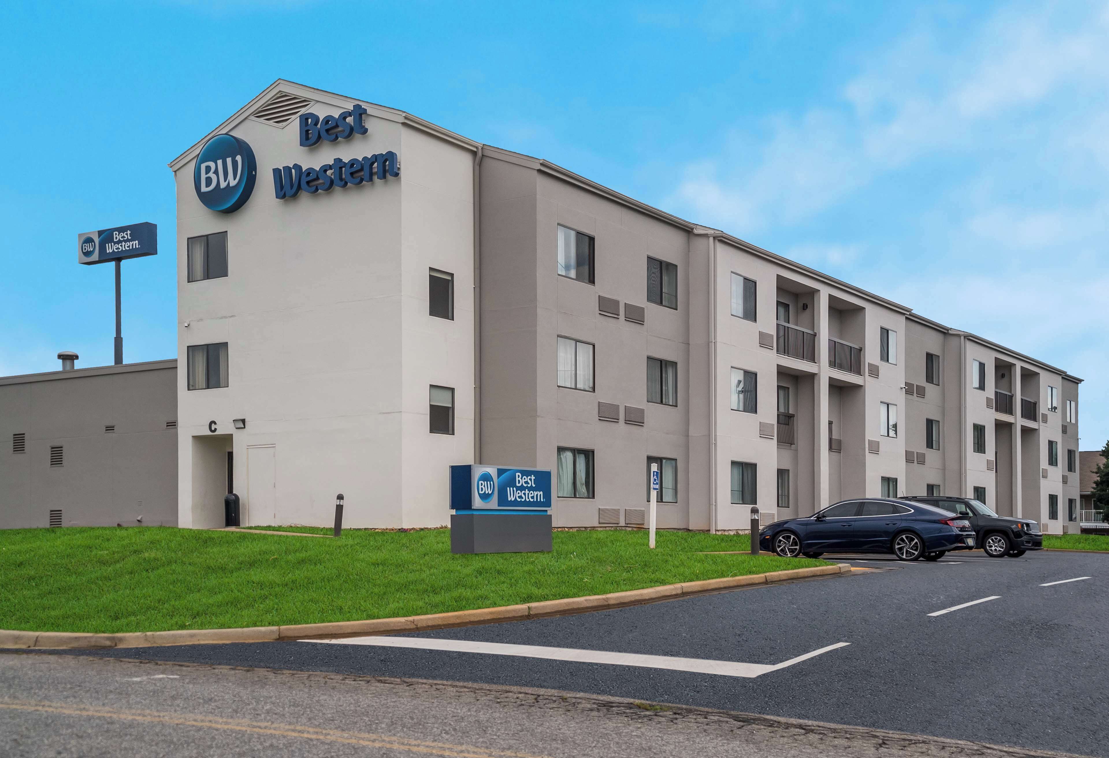 Un bâtiment d’hôtel Best Western, avec une enseigne, un parking et deux voitures garées devant.