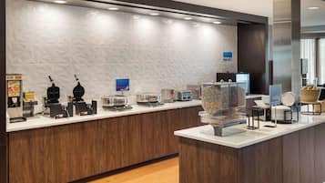 A modern reception desk with a patterned wall, a coffee machine, a scale, and a display of pillows.