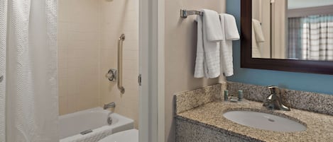 Baño con ducha, inodoro, lavamanos y espejo.