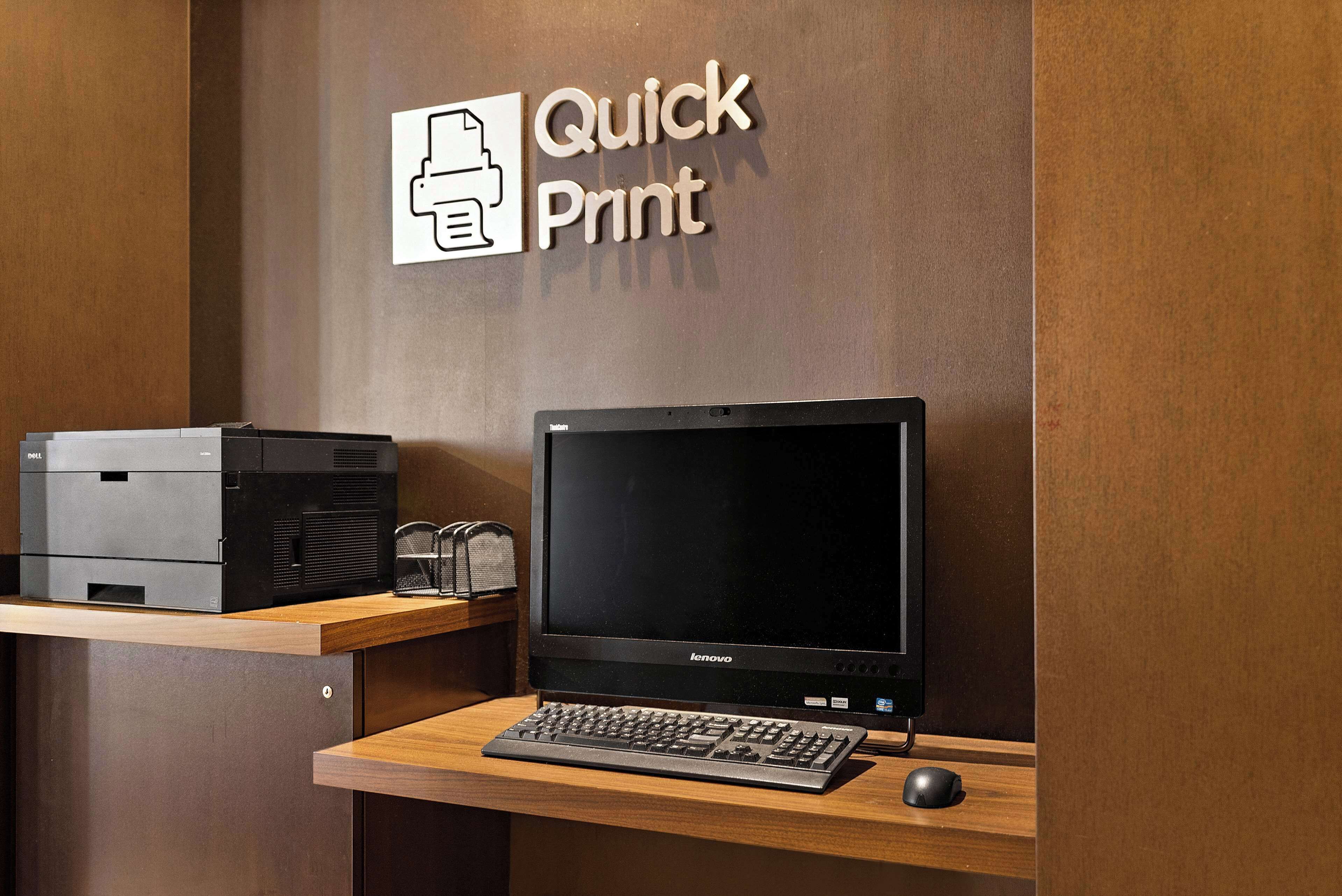 Een bureau met een printer, een monitor en een toetsenbord.