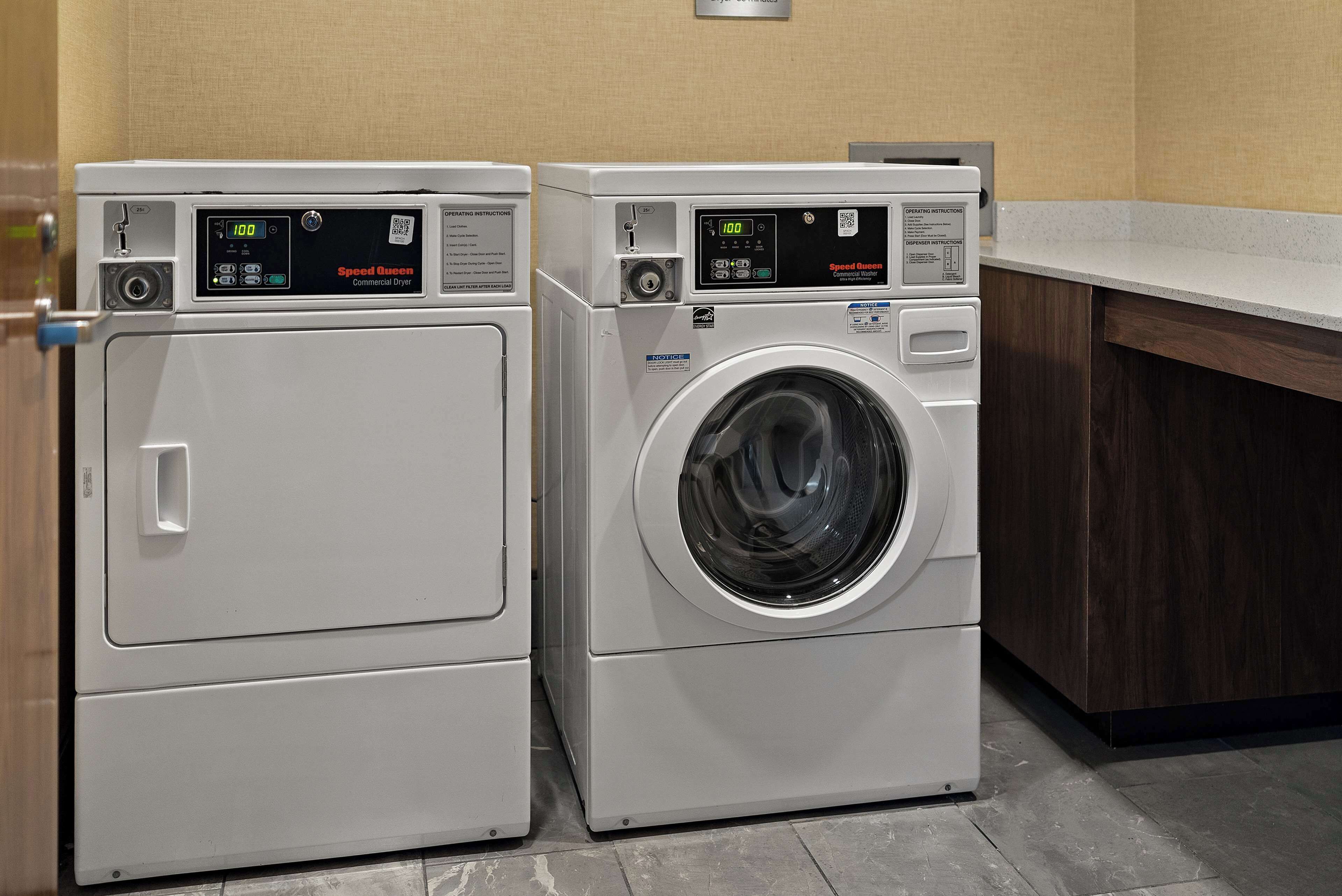 Two front-loading washing machines in a laundry area with a wooden cabinet and a countertop.