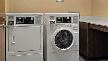 Two front-loading washing machines in a laundry area with a wooden cabinet and a countertop.