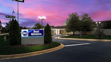 A Best Western hotel sign, a street sign, and a well-maintained road with a clear sky.