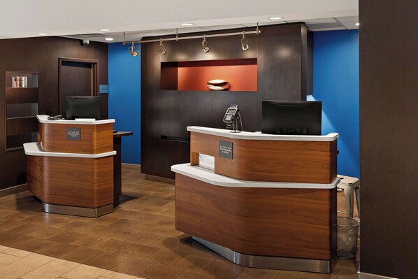 Un área de recepción con dos mostradores de madera, una pared de acento azul y un televisor montado.