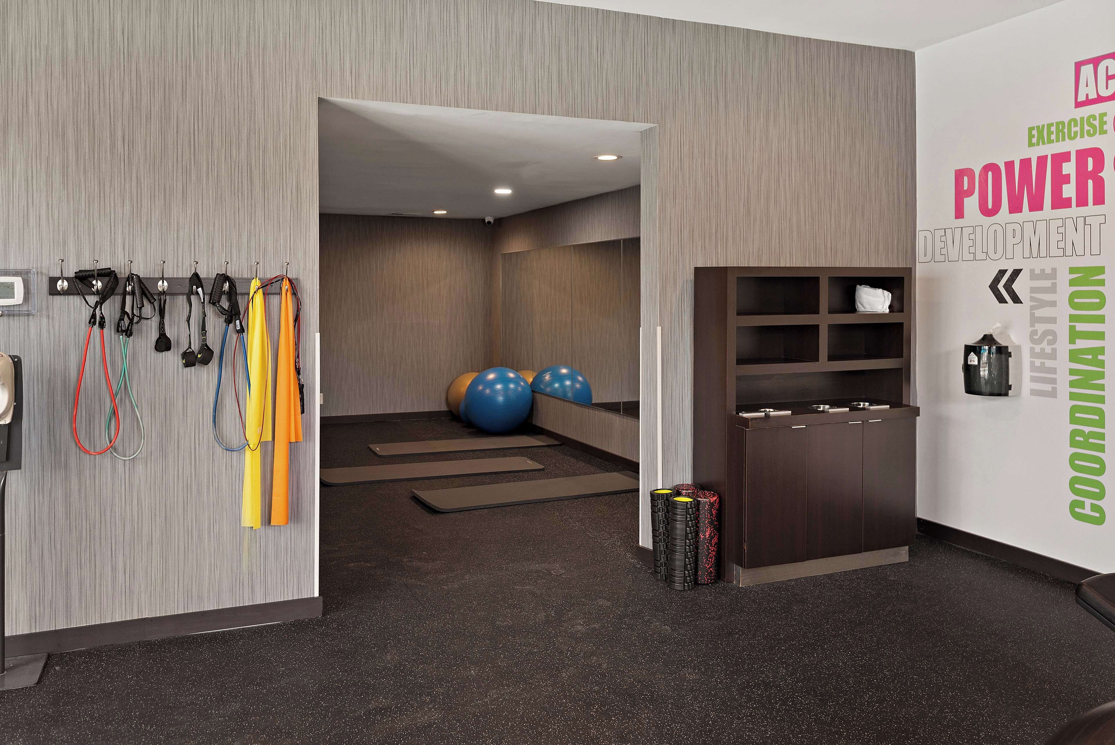 A modern fitness room with exercise equipment, a wall with motivational text, and a reception area.