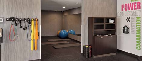 A modern fitness room with exercise equipment, a wall with motivational text, and a reception area.