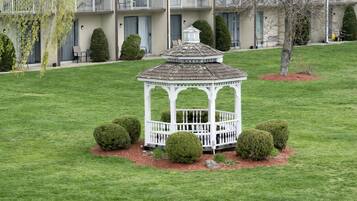 A gazebo in a well-maintained lawn with a building in the background.