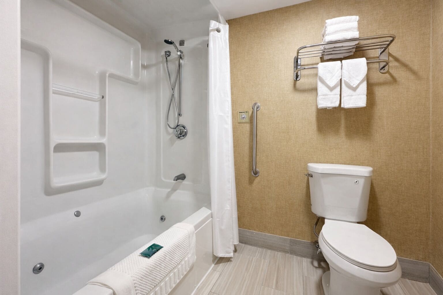 Ein Badezimmer mit einer Badewanne, einer Toilette, einem Handtuchhalter und einer Haltestange.