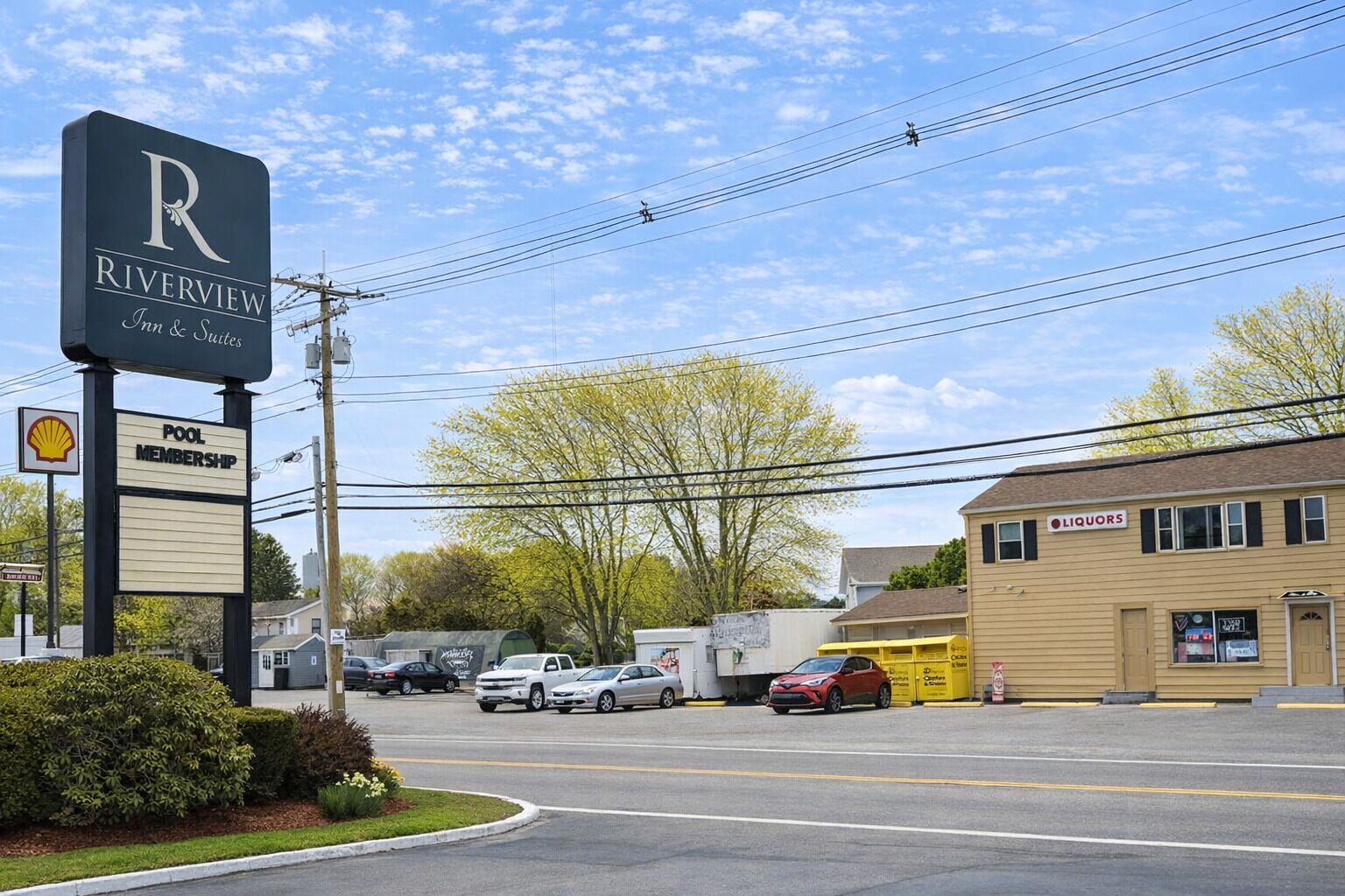 A Riverview Inn & Suites sign, a pool membership sign, a Shell gas station, and a liquor store.