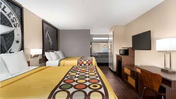 A hotel room with two beds, a desk, a TV, and a mirror.