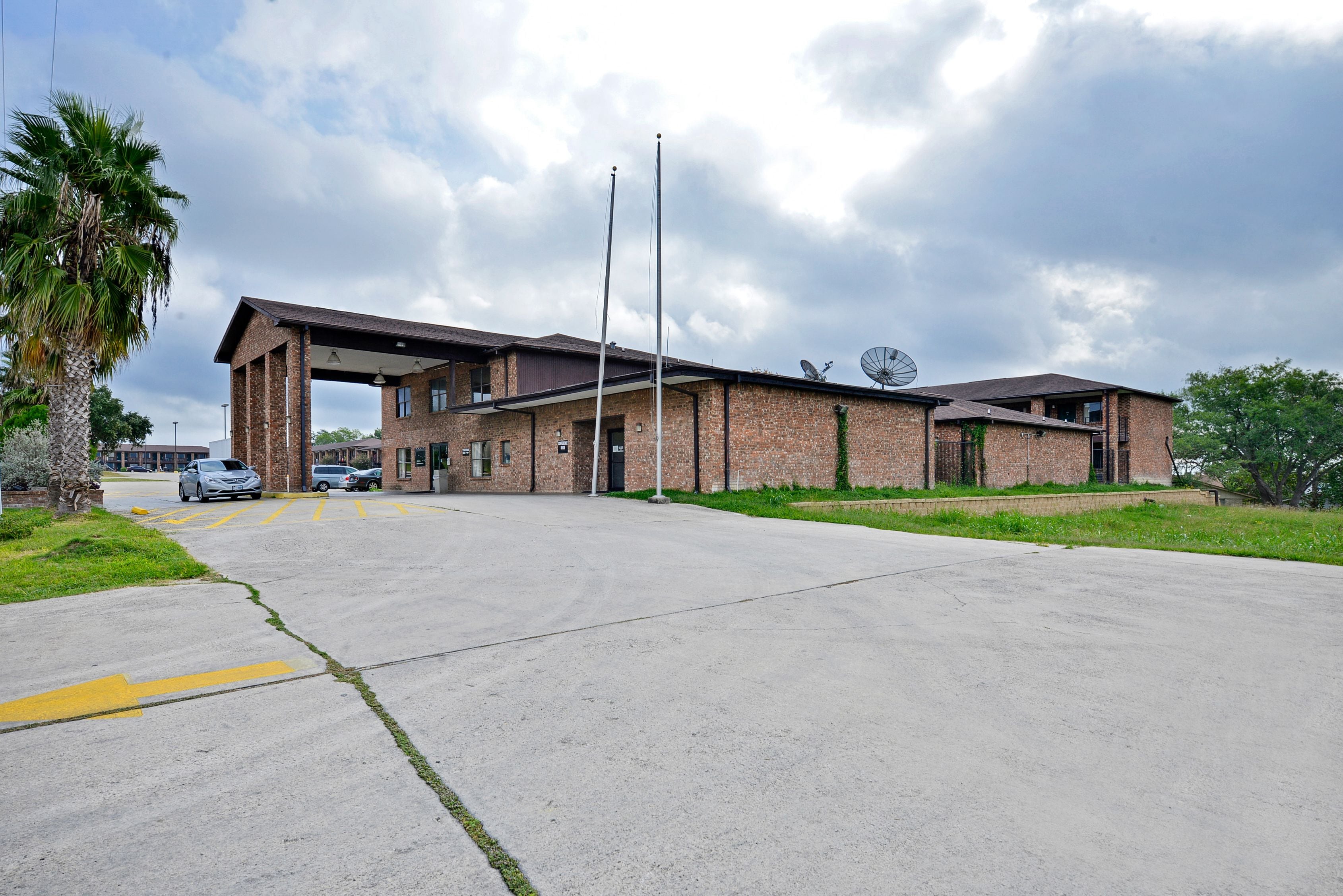 A building with a covered entrance, brick walls, and a satellite dish.