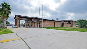 A building with a covered entrance, brick walls, and a satellite dish.