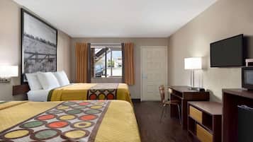 A hotel room with two beds, a desk, a chair, a television, and a window with curtains.
