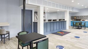 A modern hotel lobby with a reception desk, seating area, and a kitchen visible in the background. - Super 8 by Wyndham Universal City (Universal City)