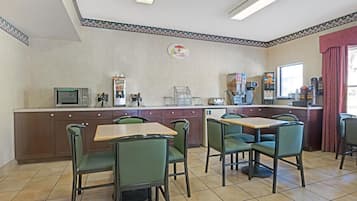A restaurant with a counter, chairs, and a microwave.