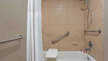 A bathroom with a bathtub, a shower, and a grab bar.
